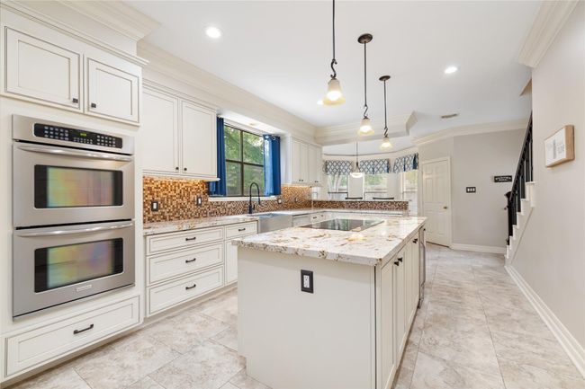 Designed for both function and style, the kitchen features double ovens, a spacious center island with electric cooktop, granite countertops, and thoughtful details like pots-and-pans drawers and under-cabinet lighting—perfect for everyday meals or hosting a crowd. | Image 17