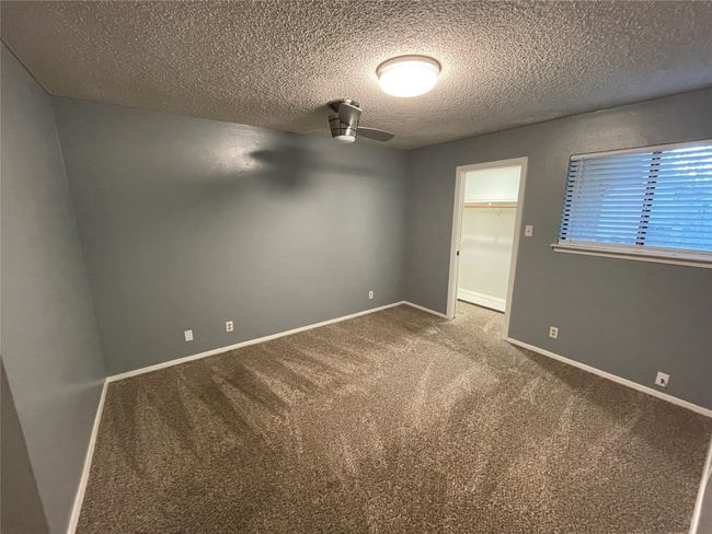 Empty room with carpet, ceiling fan, and a textured ceiling | Image 14