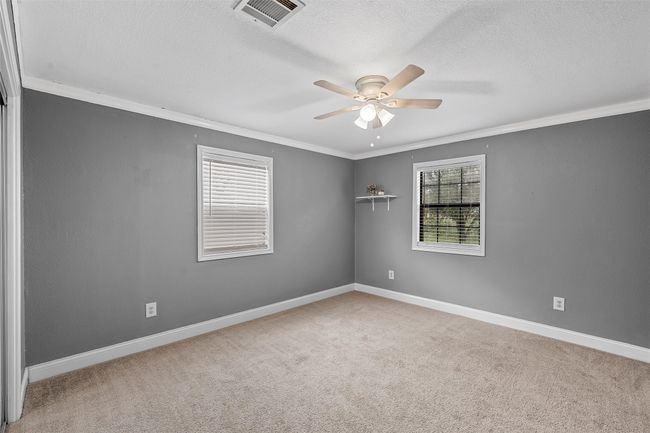 Empty room featuring ornamental molding, a ceiling fan, carpet flooring, and a textured ceiling | Image 20