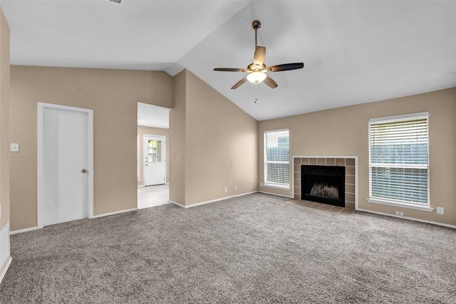 Unfurnished living room featuring a ceiling fan, carpet floors, a healthy amount of sunlight, and a fireplace | Image 8