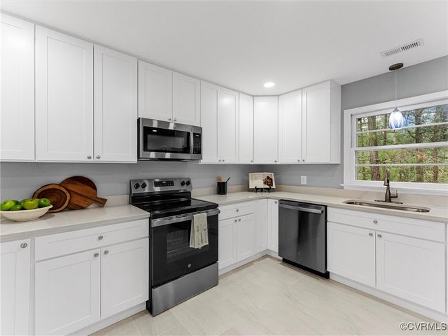 Kitchen featuring appliances with stainless steel finishes, white cabinets, light countertops, and a sink | Image 21