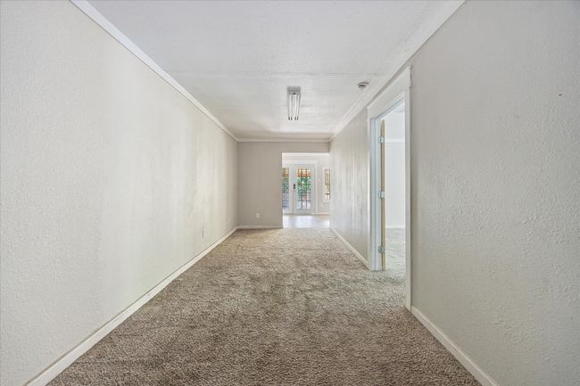 Corridor with carpet floors, a textured wall, and crown molding | Image 14