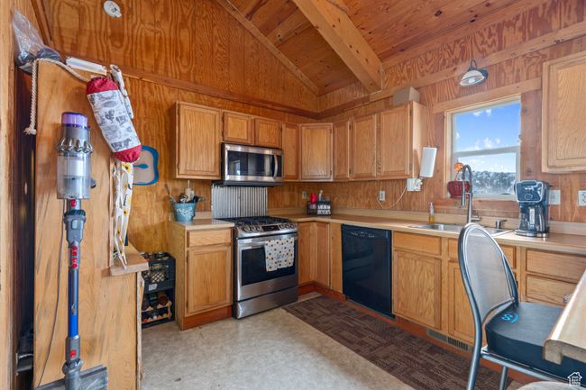 Kitchen with wooden walls, sink, wood ceiling, and appliances with stainless steel finishes | Image 21