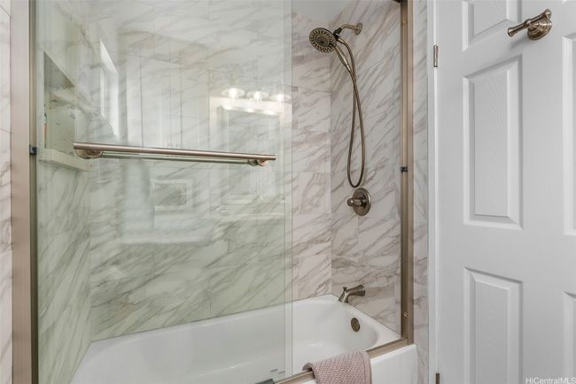 This guest bathroom has a tub/shower with glass enclosure. The primary bedroom ensuite has a walk-in shower. | Image 23