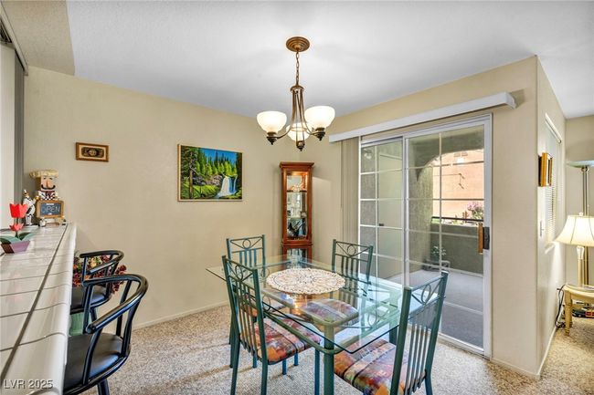Carpeted dining space with baseboards and a notable chandelier | Image 26