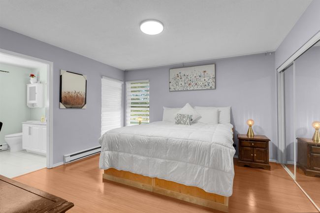 Bedroom featuring a baseboard radiator, a closet, wood finished floors, and ensuite bathroom | Image 8