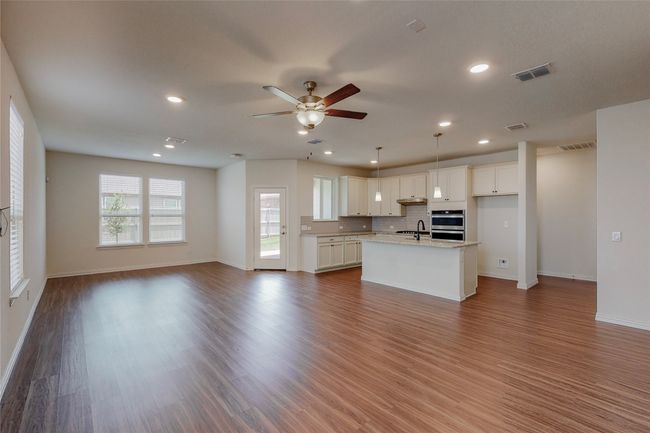 Kitchen with open floor plan, double oven, ceiling fan, a sink, and white cabinetry | Image 6