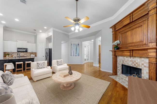 Living room featuring a ceiling fan, recessed lighting, crown molding, a tiled fireplace, and light wood finished floors VIRTUALLY STAGED | Image 14