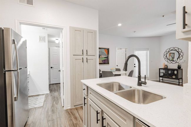 Kitchen featuring light stone countertops, light wood-type flooring, stainless steel refrigerator, and sink | Image 13