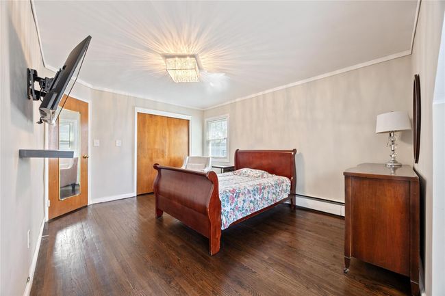 Bedroom featuring crown molding, dark wood-style flooring, baseboards, and a baseboard radiator | Image 12