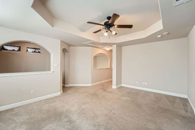 Unfurnished room with light colored carpet, a raised ceiling, a ceiling fan, baseboards, and visible vents | Image 34