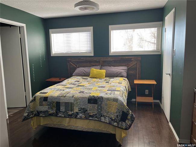 Bedroom with a textured ceiling, dark wood-style flooring, multiple windows, and baseboards | Image 28