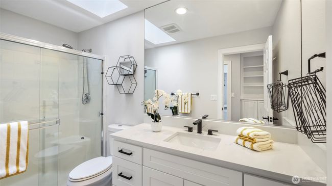 The second upstairs bathroom offers abundant storage, stylish white countertops, a spacious walk-in shower, a large mirror, and a skylight that brightens the room. This 3/4 bath combines function and natural light beautifully | Image 30