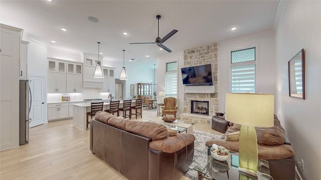 Living area with ornamental molding, ceiling fan, light wood finished floors, a fireplace, and recessed lighting | Image 5