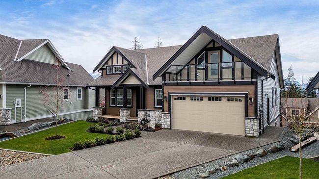 View of front of home featuring stone siding, roof with shingles, concrete driveway, an attached garage, and a front lawn | Image 7