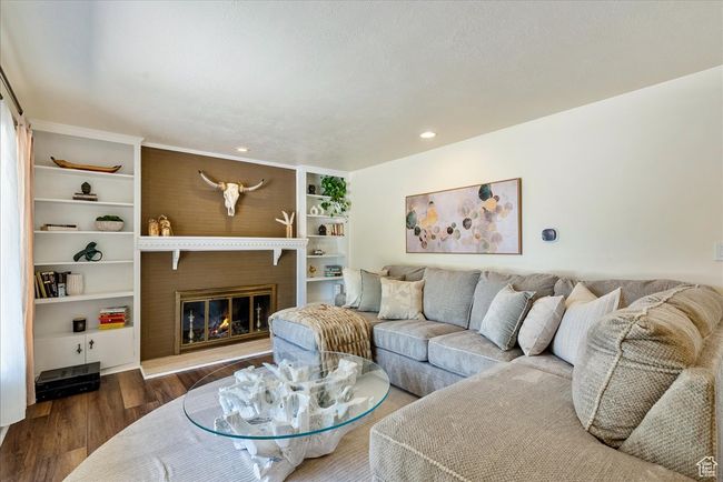 Living room featuring wood finished floors, recessed lighting, a fireplace, and built in features | Image 11