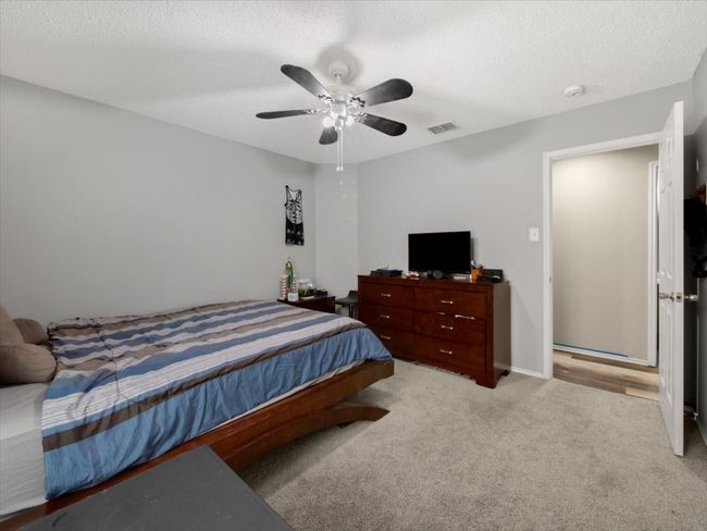 Bedroom with a textured ceiling, ceiling fan, and light colored carpet | Image 23