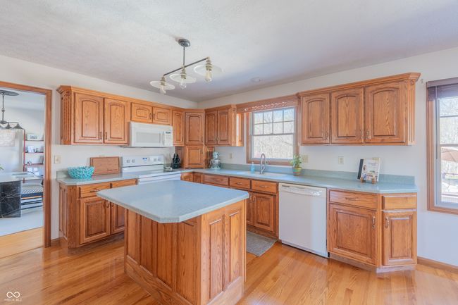 kitchen featuring light countertops, light wood-style floors, a sink, and white appliances | Image 13