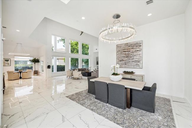 The walls are adorned with a subtle, contemporary palette, allowing the chandelier to truly shine. Large windows frame the room, offering beautiful views and an abundance of natural light that enhances the room's airy feel. The dining area is perfectly sized for both intimate family dinners and larger gatherings, making it a versatile space for any occasion. | Image 8