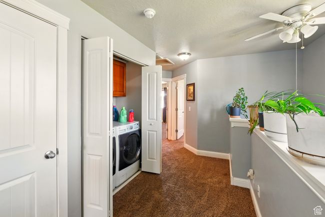 Washroom featuring washer and clothes dryer, dark colored carpet, baseboards, ceiling fan, and a textured ceiling | Image 24