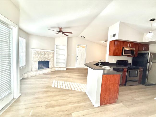 Kitchen featuring dark countertops, ceiling fan, a peninsula, stainless steel appliances, and lofted ceiling | Image 4