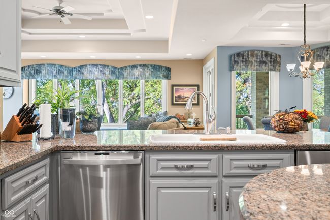 kitchen with a healthy amount of sunlight, a tray ceiling, dishwasher, and a sink | Image 30