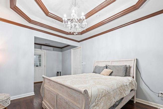 Bedroom with a chandelier, crown molding, a wall mounted air conditioner, and dark wood-type flooring | Image 20