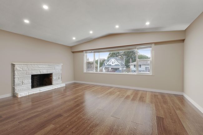 Unfurnished living room with lofted ceiling, a fireplace, wood finished floors, and baseboards | Image 12