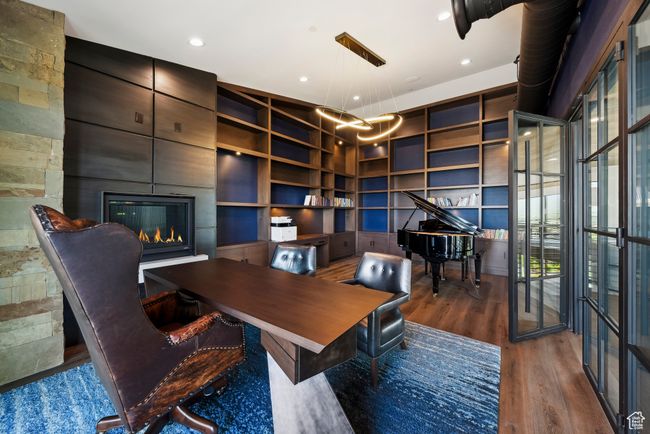 Home office featuring a fireplace, wood finished floors, built in shelves, and recessed lighting | Image 108
