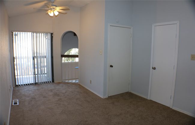 Empty room with carpet flooring, ceiling fan, and high vaulted ceiling | Image 18