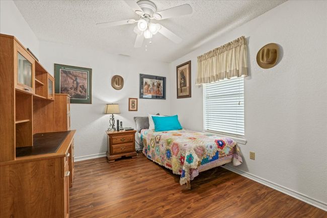 Bedroom featuring a textured ceiling, dark wood-style flooring, and a ceiling fan | Image 24