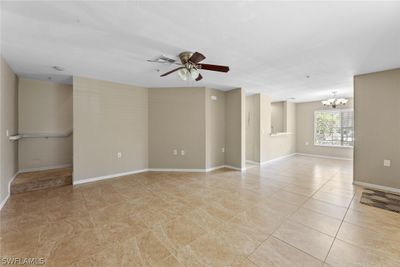 Spare room featuring ceiling fan with notable chandelier and light tile floors | Image 3