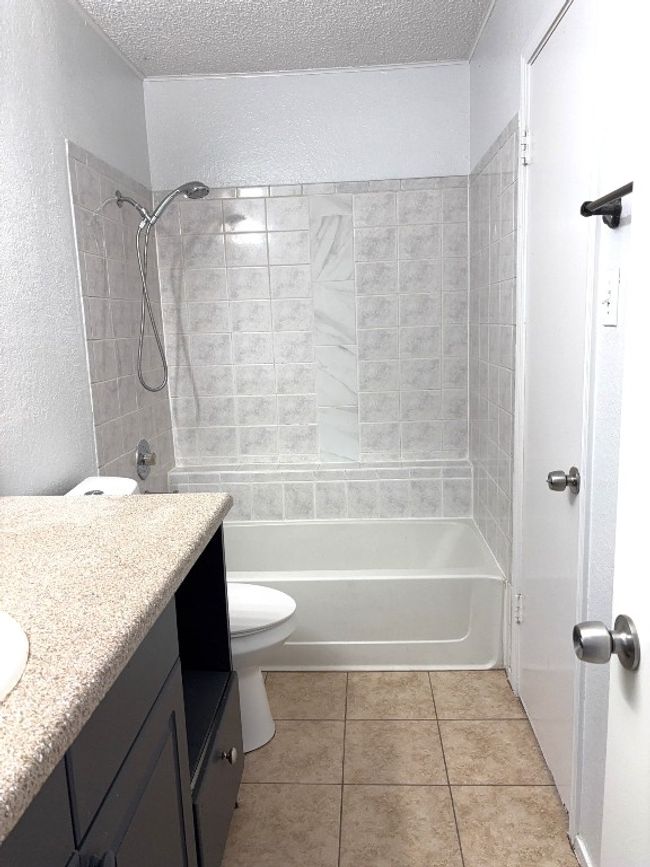Full bathroom featuring vanity, a textured wall, tub / shower combination, tile patterned floors, and a textured ceiling | Image 10