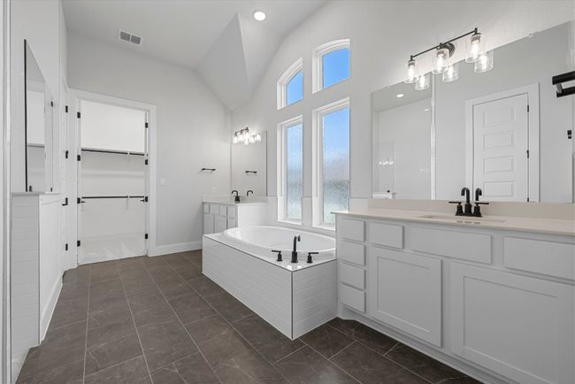 Bathroom with marble look tile flooring, plenty of natural light, vaulted ceiling, two vanities, and a garden tub | Image 29