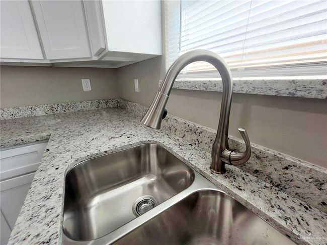 Kitchen view of white cabinetry and light stone counters | Image 6