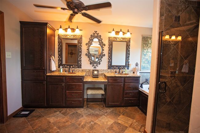Bathroom featuring double vanity, ceiling fan, a garden tub, a shower stall, and stone finish flooring | Image 11