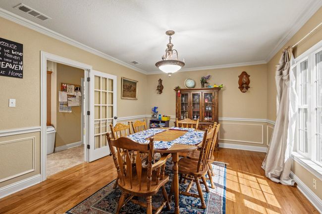 Dining space with ornamental molding, light wood finished floors, and visible vents | Image 11