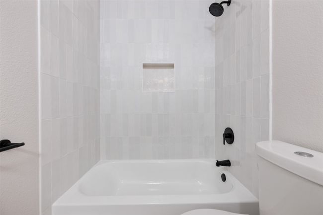 Bathroom featuring toilet, a textured wall, and shower combination | Image 35