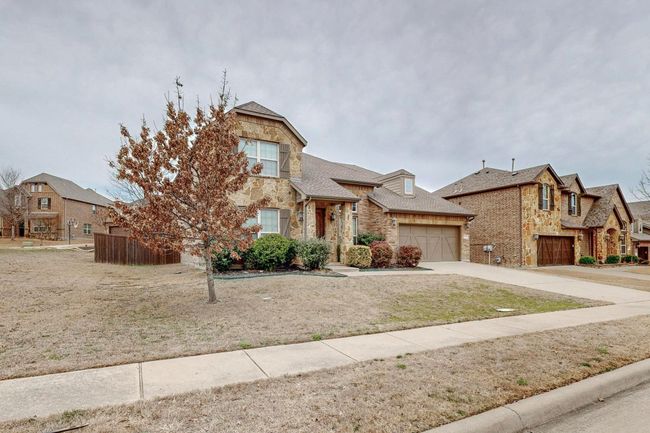 View of front of home with stone siding, concrete driveway, and an attached garage | Image 6