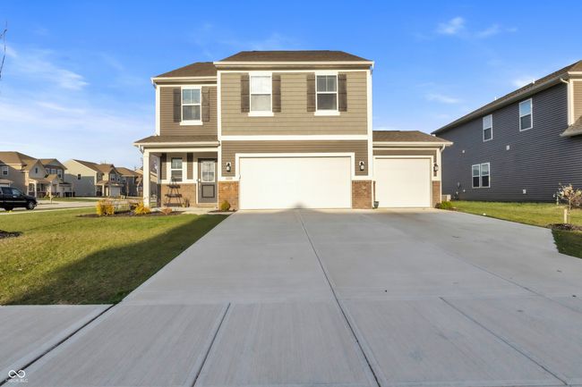 view of front of house featuring concrete driveway, a front yard, a garage, and brick siding | Image 40
