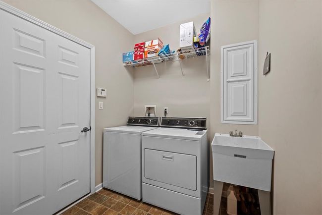 This laundry room acts as a mudroom that leads from the garage into the house. Washer and dryer will convey if buyer would like. A utility sink comes in handy for various house needs. | Image 26