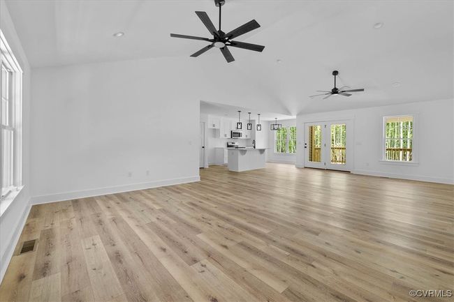 Unfurnished living room featuring a ceiling fan, baseboards, light wood-type flooring, and visible vents | Image 5