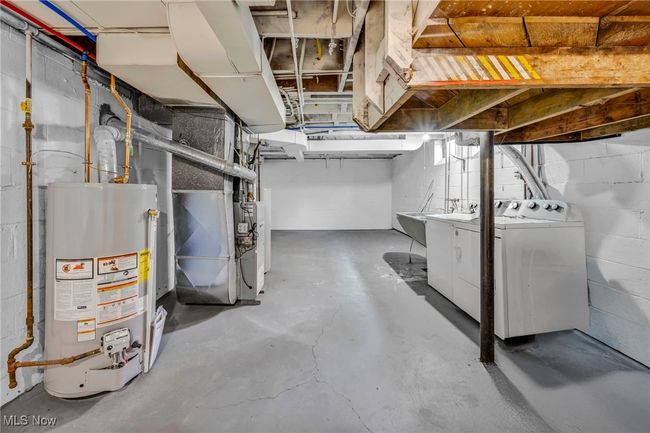 Unfinished below grade area with washer and dryer, heating unit, and water heater | Image 23