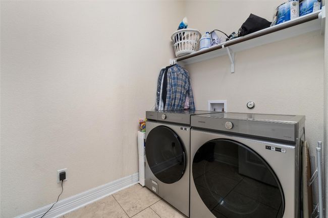 Laundry area with baseboards, washing machine and dryer, laundry area, and light tile patterned floors | Image 28