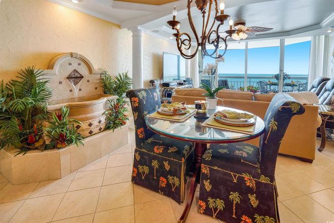 Tiled dining area with ornamental molding, a chandelier, decorative columns, a water view, and a textured wall | Image 14