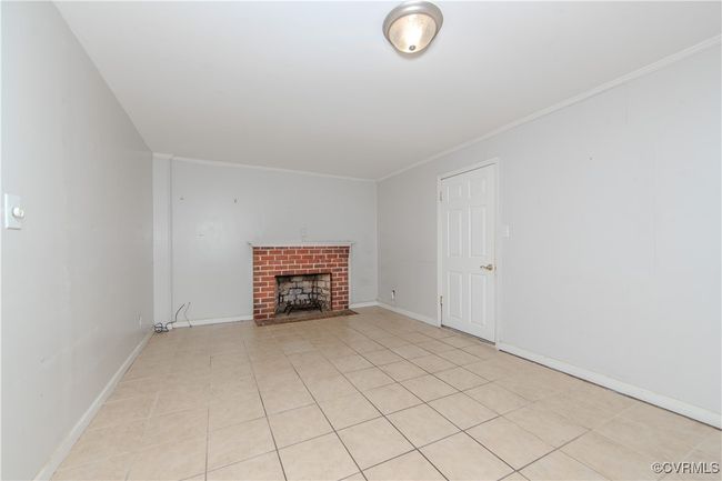 Unfurnished living room featuring crown molding, light tile patterned flooring, and a brick fireplace | Image 12