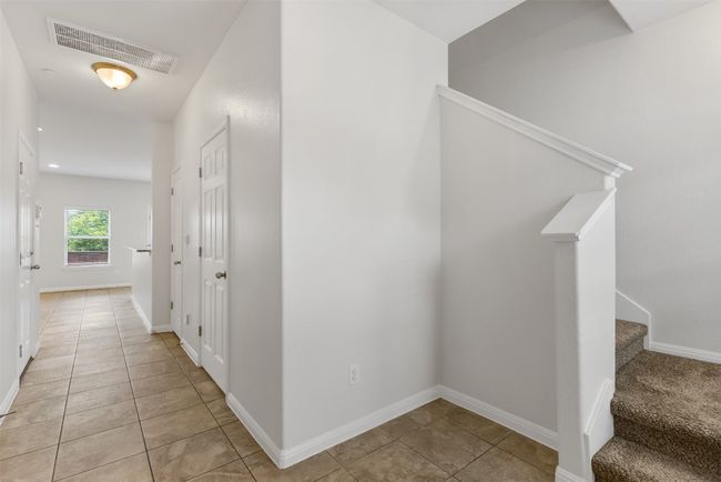 Hallway with light tile patterned floors and stairway | Image 6