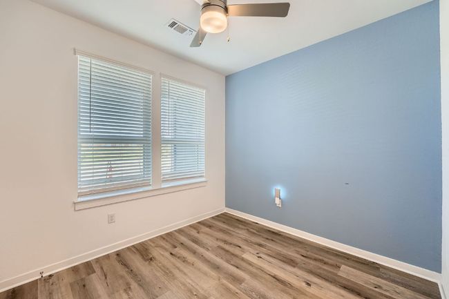 Spare room with wood finished floors, baseboards, ceiling fan, and visible vents | Image 9
