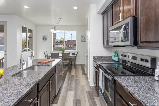 Kitchen featuring a sink, a chandelier, stainless steel appliances, light wood-style floors, and stone countertops | Image 8