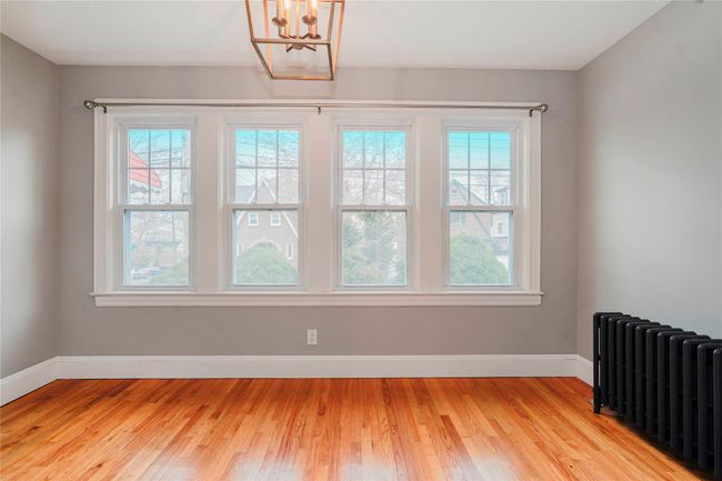 Unfurnished room with baseboards, radiator, a notable chandelier, and light wood-style floors | Image 5
